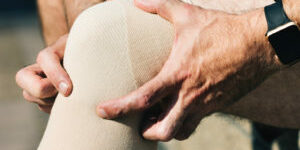 Two male hands holding a knee with a brace